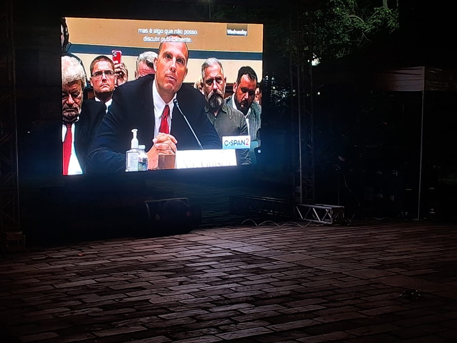 Telão ao ar livre, à noite, exibindo um vídeo para o público do encontro