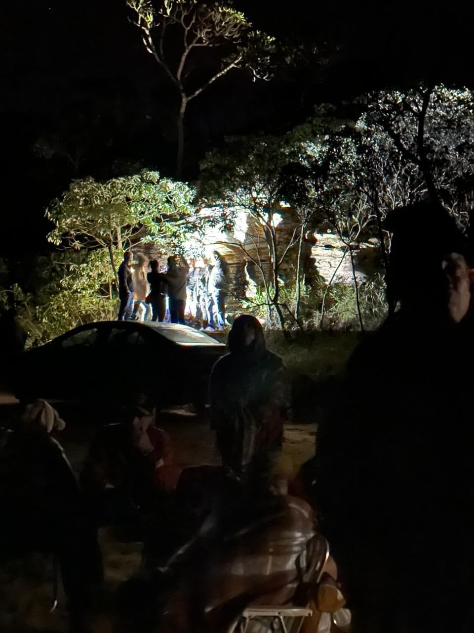 Grupo chegando à pedra de noite, entre as árvores