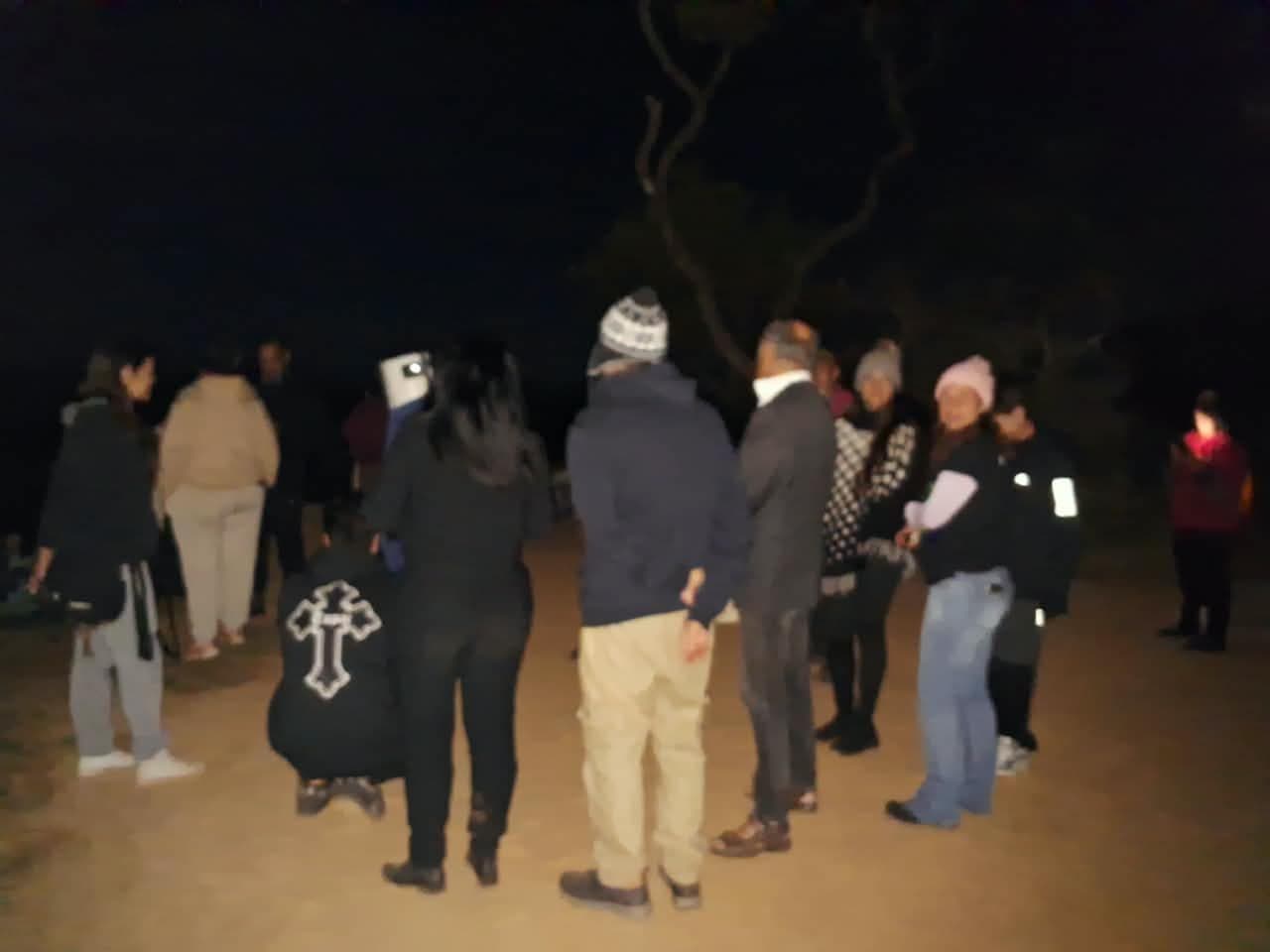 Grupo reunido em pé no platô, de noite
