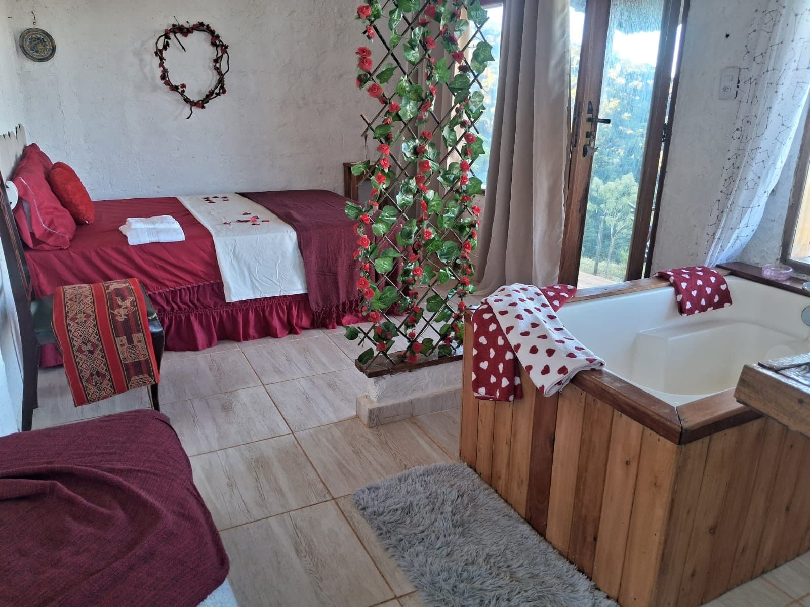 O quarto inteiro: a cama vermelha e a banheira, separadas por uma treliça de flores