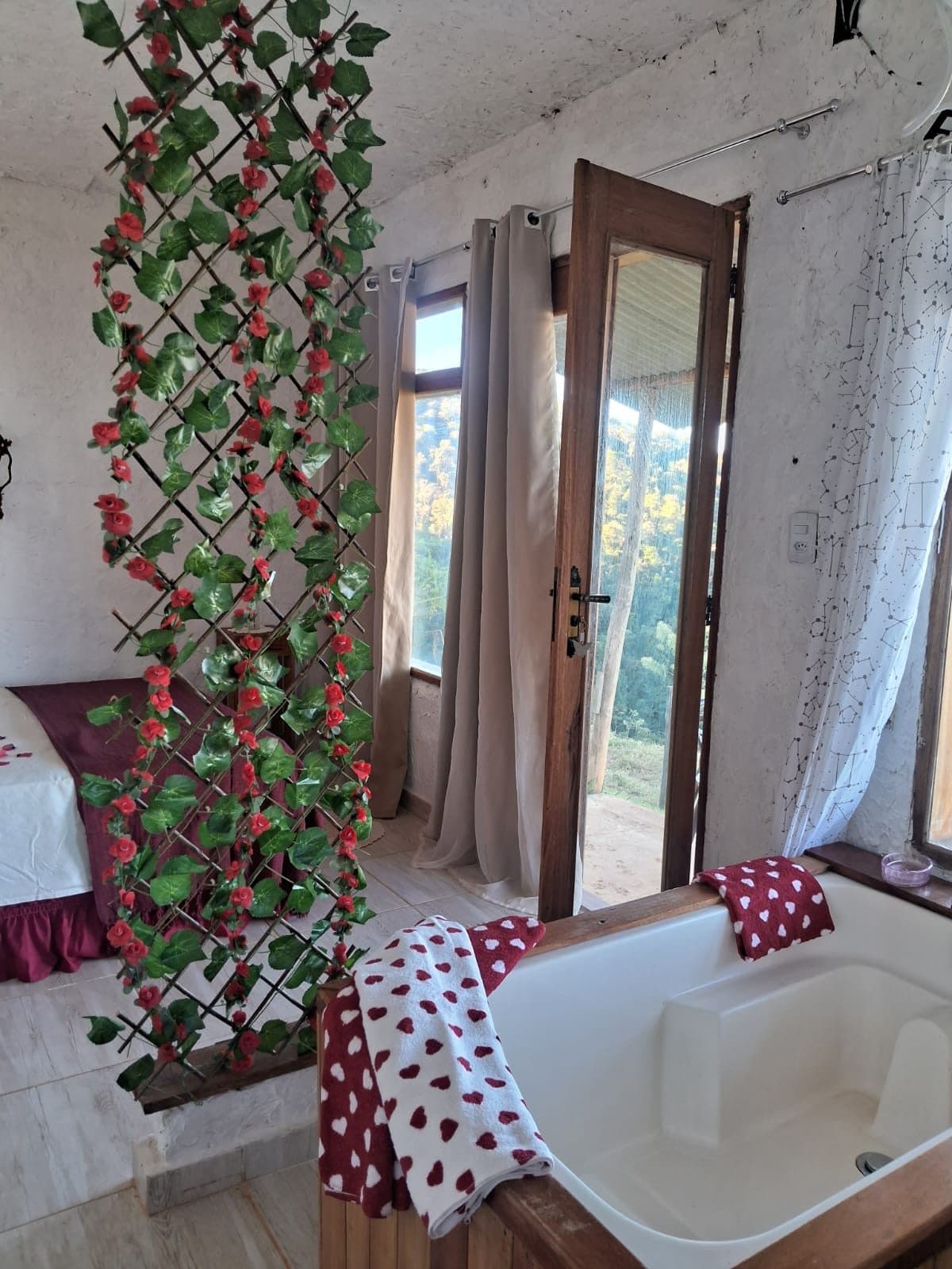 Treliça de flores vermelhas entre a banheira e a porta da varanda