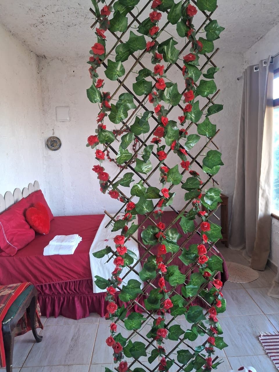 A cama vermelha vista através da treliça de flores